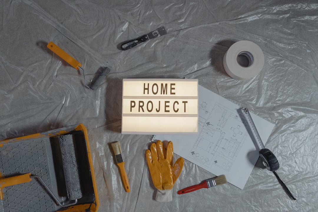 The image depicts a DIY home project setup with tools, a blueprint, and a "HOME PROJECT" sign, conveying creativity and hands-on work.